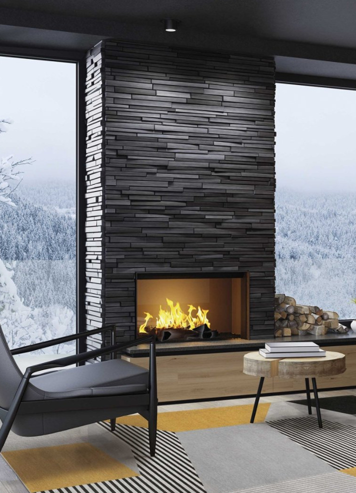 Szaro-żółty dywan nowoczesny przy kominku w salonie z widokiem na zimowy krajobraz i ścianą z ciemnego kamienia